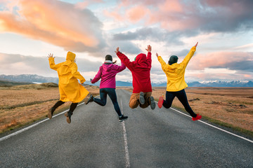 four friend jump on the road at sunset