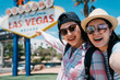 © PR Image Factory - Close up lifestyle portrait of girls best friends make self picture and laughing together. Two japanese women traveler take selfie and showing blurred las vegas sign on back in sunny day in summer