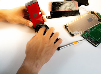  On the desk . repairman is changing the mobile phone screen for customers.