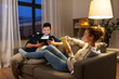 © Syda Productions - leisure and people concept - happy couple with tablet computer and book at home in evening