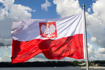 Flag of Poland. Poland national flag with emblem  on cloudy blue sky.