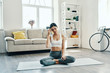 © gstockstudio - Just a minute to rest. Beautiful young woman in sports clothing practicing yoga and drinking yoga while spending time at home