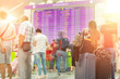 © Kyryl Gorlov - Motion blurred travellers crowd looking at fligh feparture and arrival timetable at airport terminal. Travel and tourism concept. Flight delay