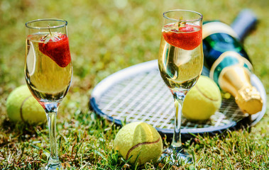 Wall Mural - Tennis game. Strawberries, champagne and tennis balls with rackets on the green grass. Sport, recreation concept