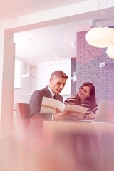 Mature male realtor and smiling female buyer reading document at table in apartment