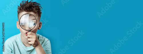 Fotomural boy in a light t-shirt looking into a large magnifying glass