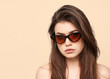 sunglasses girl, close up studio shot of beautiful fashion young woman model with long hair looking at camera . while posing against clean cream blank copy space wall for your content