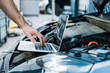 © LIGHTFIELD STUDIOS - cropped view of auto mechanic using laptop with blank screen near car