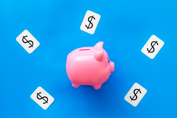 Business and budget concept with piggy bank and dollar sign on blue office background top view