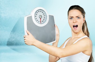 Wall Mural - Young woman hiding by scales on blue background