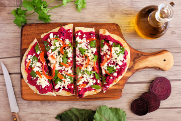 Wall Mural - Beet hummus flat bread with feta cheese. Above scene on a paddle board against a wood background. Healthy eating concept.