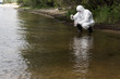 © LIGHTFIELD STUDIOS - water inspector in protective costume, latex gloves and respirator taking water sample at river