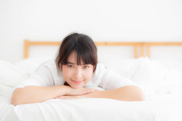 Beautiful portrait young asian woman lying and smile while wake up with sunrise at morning, girl with happy annd fun in the bedroom, lifestyle and relax concept.