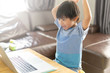 Happy asian boy in blue shirt using computer on wooden desk at home .Asian child smiling and happiness playing computer at room.