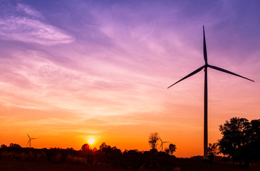 Wind turbines electric power generator on sunset sky at agriculture field