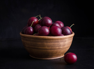 Wall Mural - ripe plums in the bowl on black background