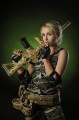 Wall Mural - beautiful blonde girl in military clothes with a gun in her hands