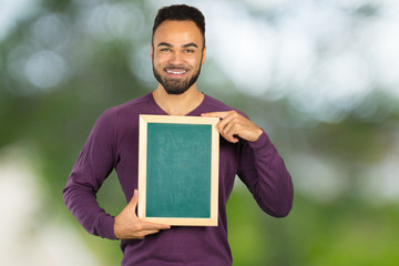 Wall Mural - Positive dark skinned male points at copy space isolated