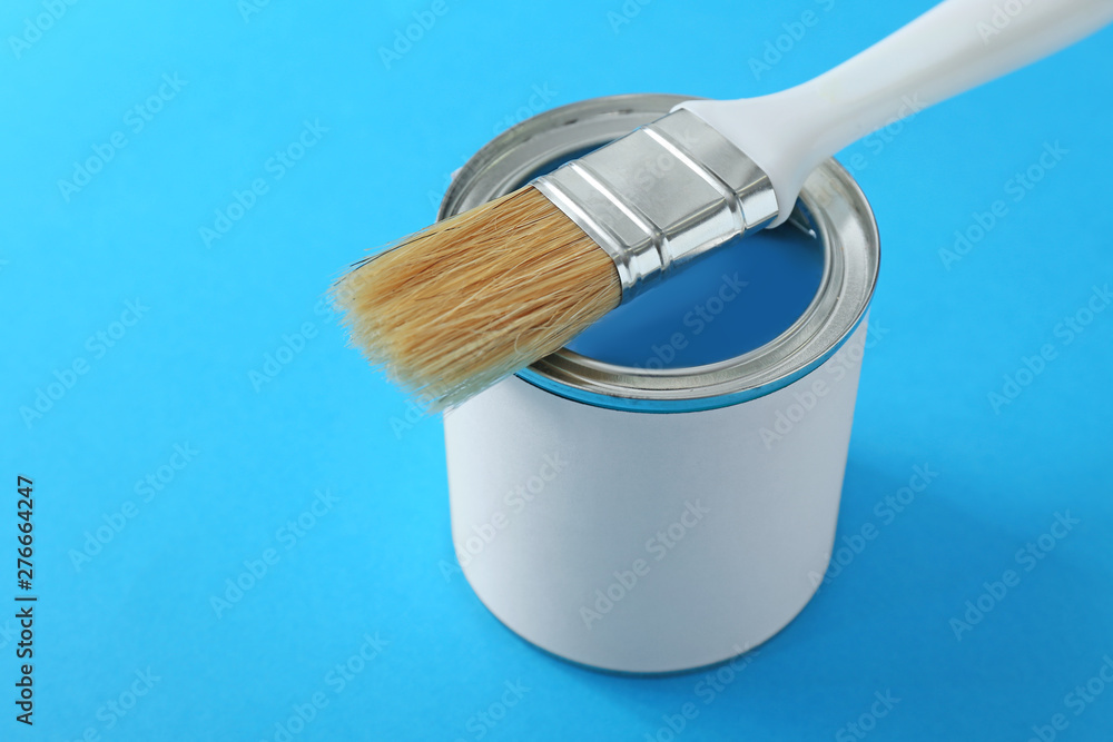 Can of paint and brush on color background