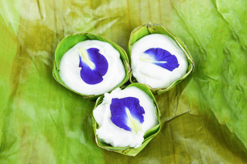 Thai pudding with coconut topping with Butterfly pea flowers on banana leaf background - Delicious Thai desserts