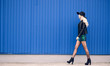© ribalka yuli - The girl in the black hat and leather jacket goes along the blue wall