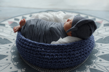 Newborn baby boy wrapped in gray fabric