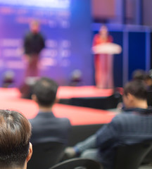 Fototapete - Speech given by female professional speaker on stage at corporate conference. Woman executive manager giving presentation to audience at leadership education workshop for entrepreneurs.