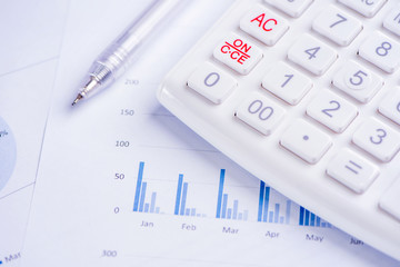 White calculator and report with chart and graph, concept of annual financial profit overview, banking and investment, close up, copy space, macro