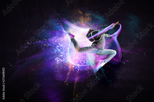 Modern female dancer jumping in hoodie with colourful splashes background. Mi...