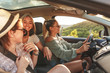 Three best female friends travel together. They drive a car and making fun. Summer adventure.	