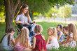 © Andrey - children hold a lesson with the teacher in the park on a green lawn.