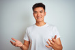 © Krakenimages.com - Young asian chinese man wearing t-shirt standing over isolated white background smiling cheerful with open arms as friendly welcome, positive and confident greetings