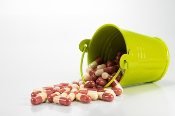 pills in green metal bucket on white background. 