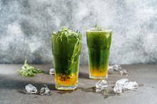 Refreshing Tarragon And Passion Fruit Lemonade. Cold Fresh Mixed Yellow Exotic Fruit With Green Herbal Plant Woodruff Drink Cocktail In Glass And Piece Of Ice Around. Tropical Liquid Side View