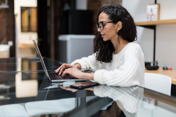 Smiling attractive young woman using laptop communicating working online at home