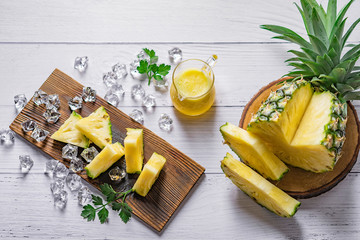 Wall Mural - Pineapple cocktail or juice with ice and pineapples on a dark background