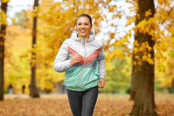 fitness, sport, people and healthy lifestyle concept - young woman running in autumn park