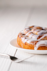 Large gourmet frosted cinnamon roll on white farmhouse table