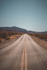 Canvas Print - Empty narrow desert road with beautiful hills in the background