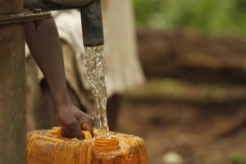 filling water jug with well water in sierra leone africa