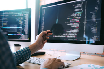 Wall Mural - software developer holds the pen pointing to the computer screen and is analyzing the code.