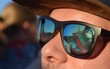 Besucher auf einem Techno-Festival spiegeln isch in den Gläsern einer Sonnenbrille