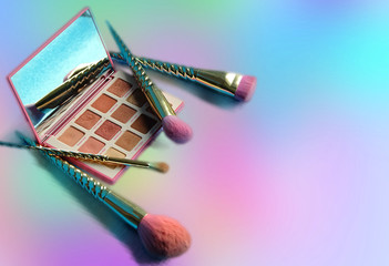 Makeup brush and decorative cosmetics on a rainbow color background , copy space