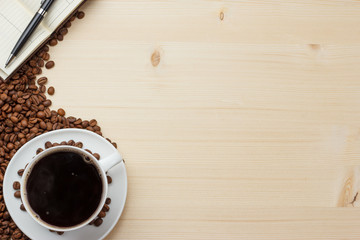 Coffee white mug on a wooden table and a notebook with a pen.