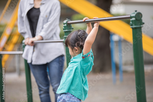 幼児の女の子が鉄棒の練習をしているのを母親が見守っている Stock 写真 Adobe Stock