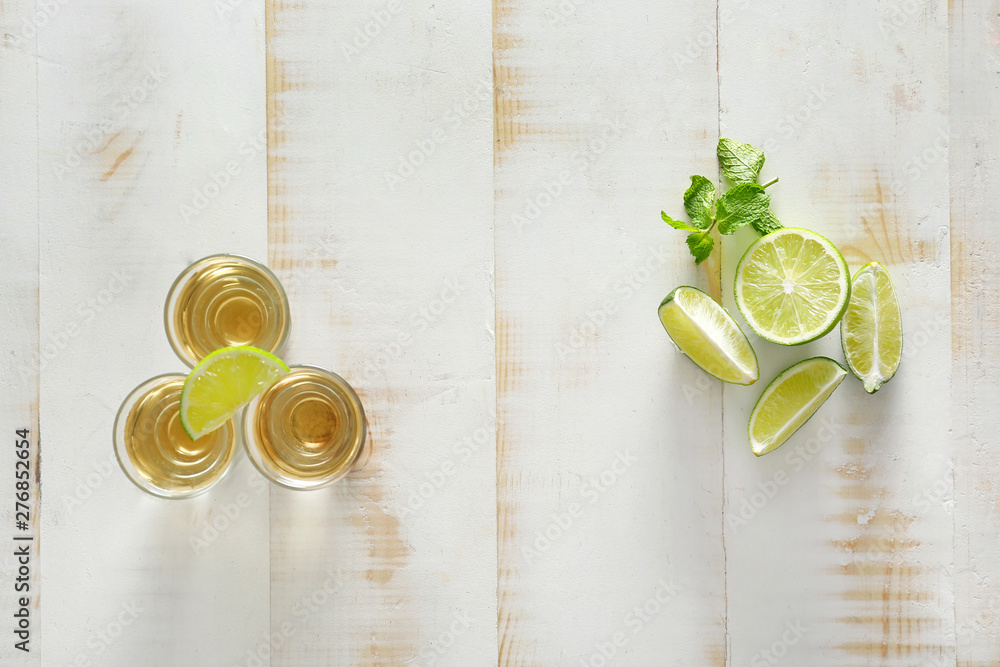 Shots of tequila and lime on wooden background