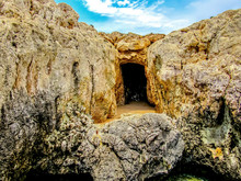 The Entrance Into A Small Dark Sea Cave Along The Rocky Shore