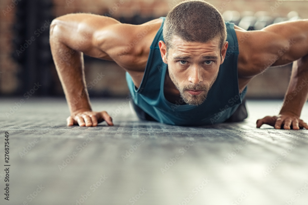 Determined man doing push ups at the gym - obrazy, fototapety, plakaty 
