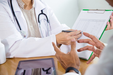 Medical consultation.Woman doctor and patient discussing something at the desk in hospital office.