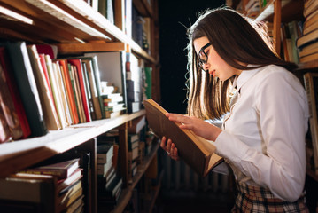 people, knowledge, education and school concept - student girl or young woman reading a book in the old library